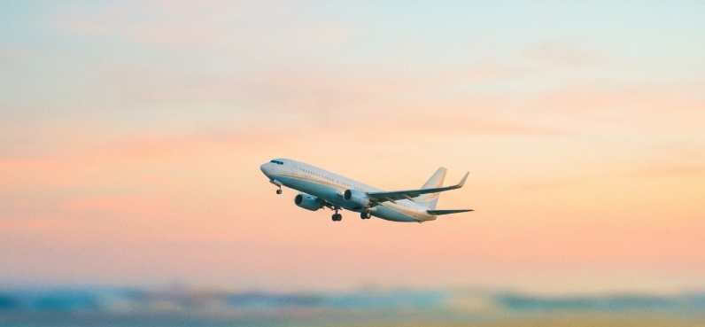 Airplane taking off into a pastel sunset sky